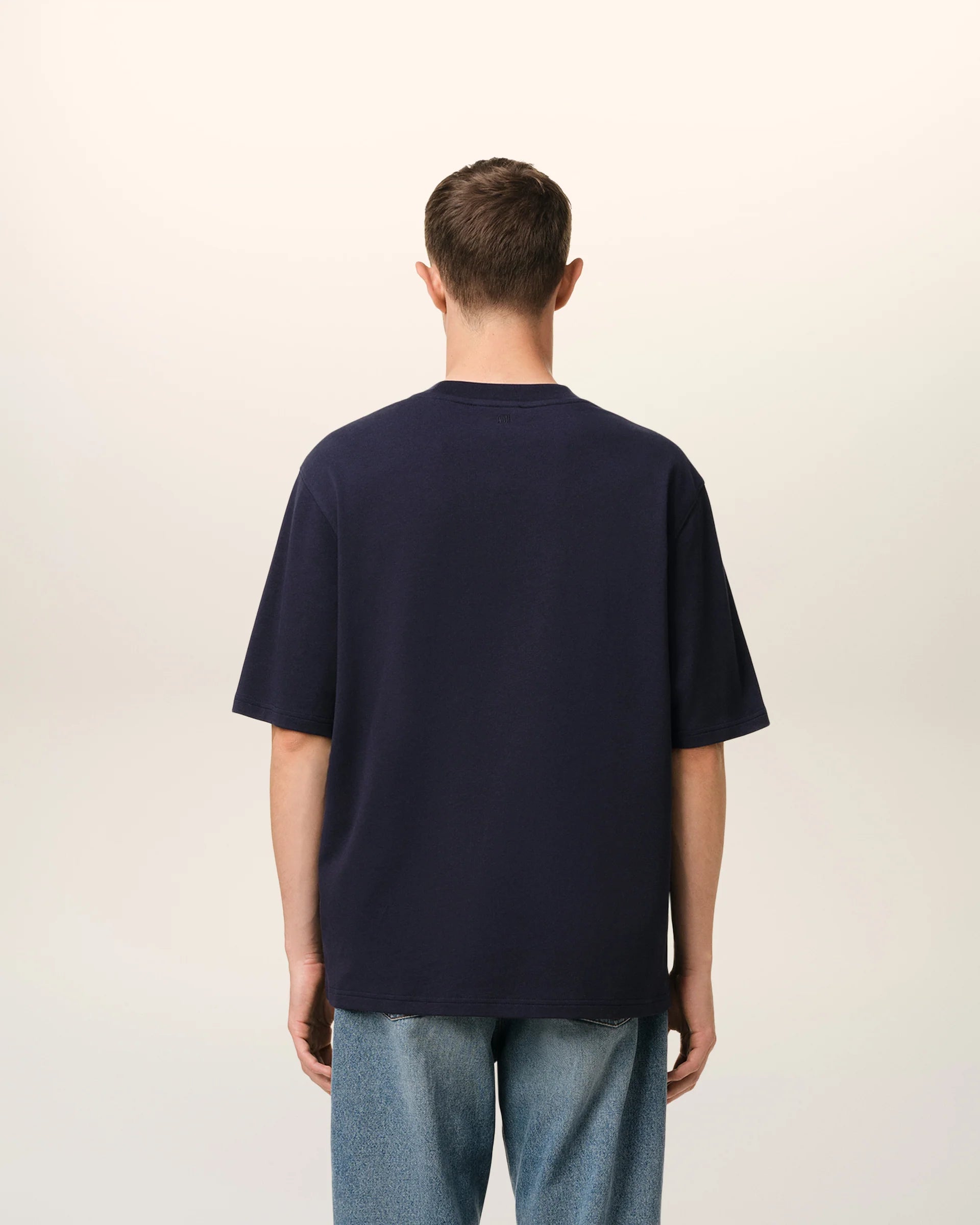 Navy blue t-shirt with 'AMI PARIS' text on a light gray background