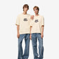 Beige t-shirt with 'AM! PARIS' text on a light gray background