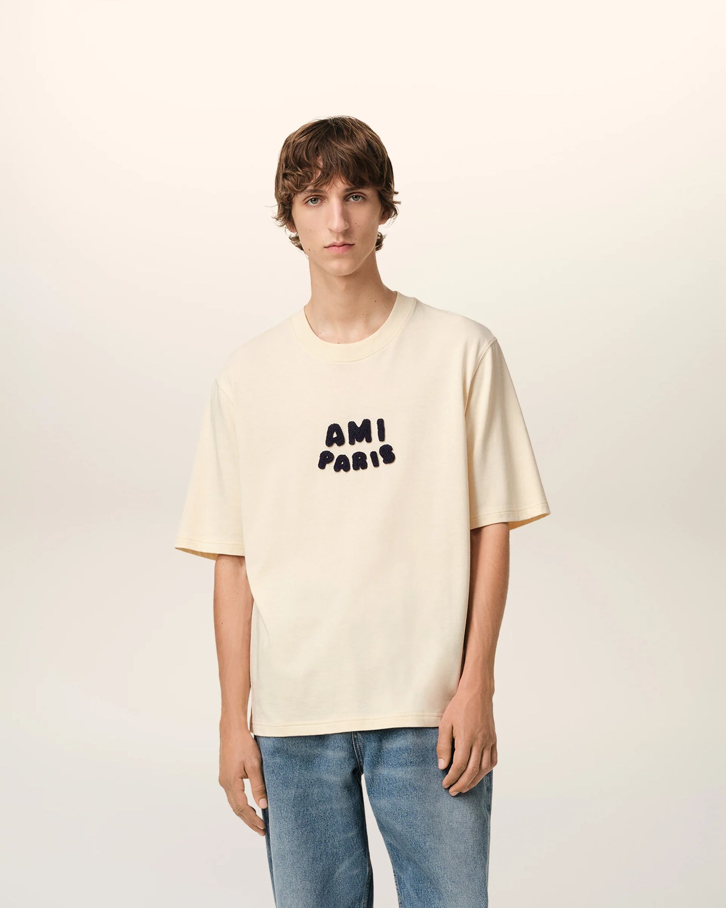 Beige t-shirt with 'AM! PARIS' text on a light gray background