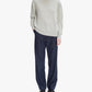 Person wearing a light gray turtleneck sweater and dark pinstripe pants on a white background