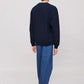 Person wearing a navy blue sweatshirt and blue jeans on a plain background
