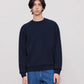 Person wearing a navy blue sweatshirt and blue jeans on a plain background