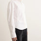 Person wearing a white shirt and black pants on a plain background