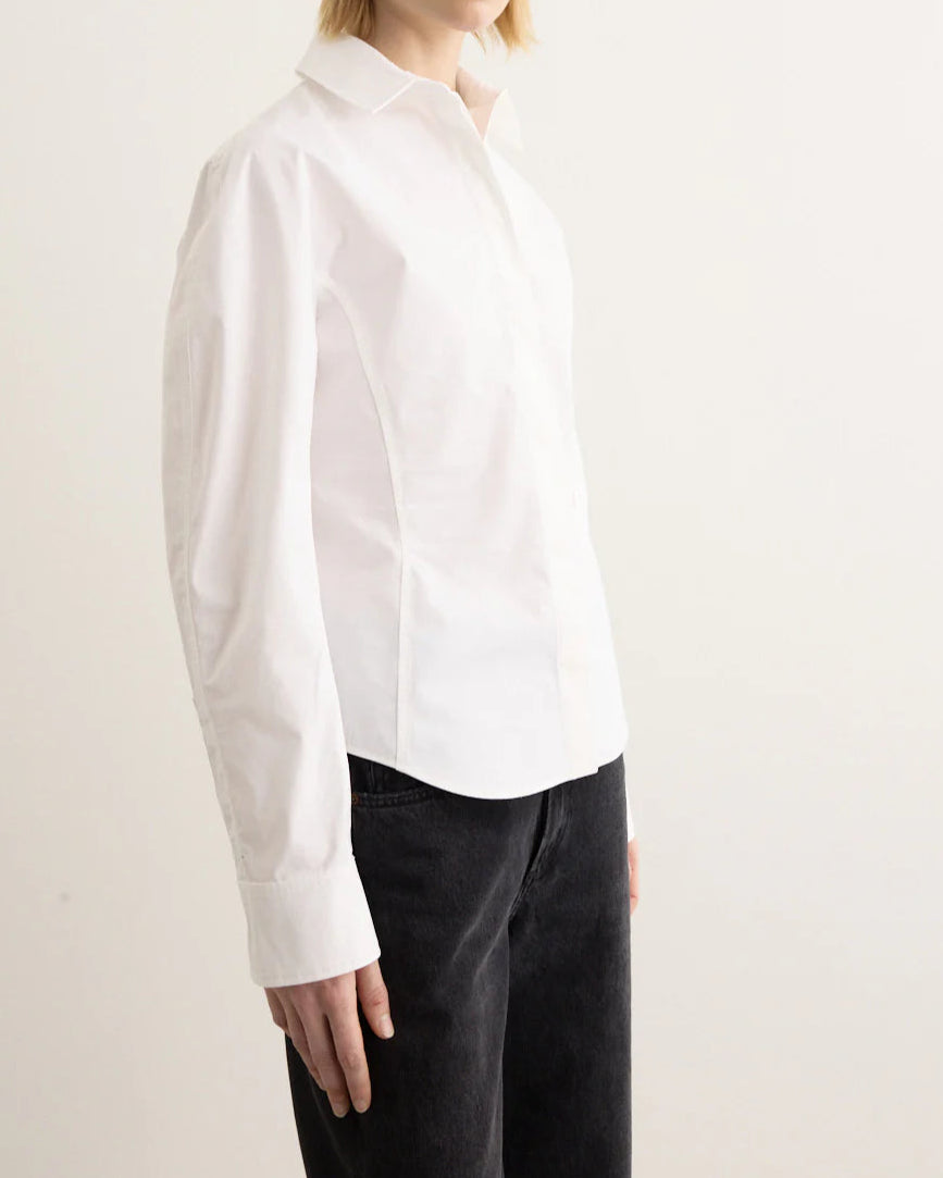 Person wearing a white shirt and black pants on a plain background