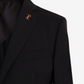 Black suit jacket with a gold brooch on a light gray background