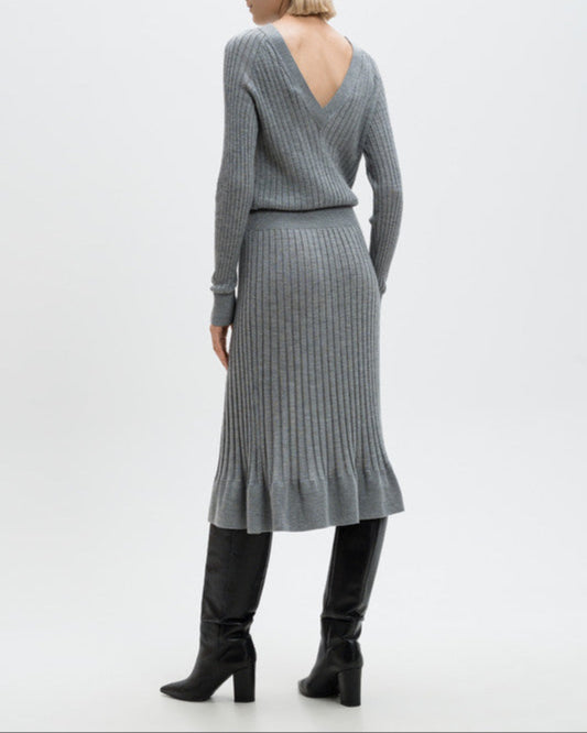 Woman wearing a gray ribbed dress with a V-neckline on a white background