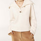 Woman wearing a cream-colored sweater with a high collar on a white background