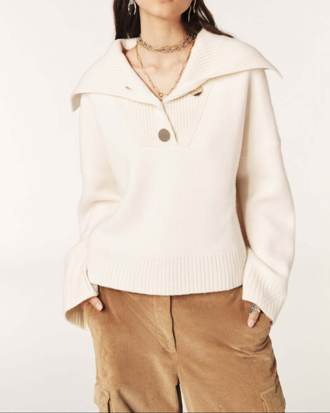Woman wearing a cream-colored sweater with a high collar on a white background