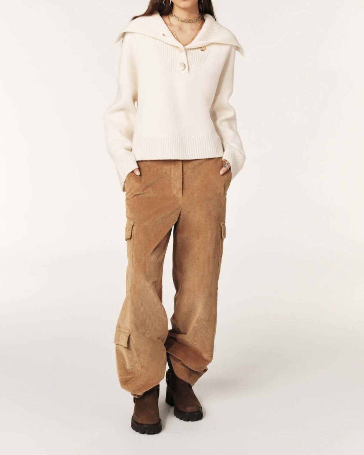Person wearing a cream hoodie and tan cargo pants on a white background
