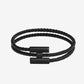 Black braided bracelet with a clasp on a light beige background