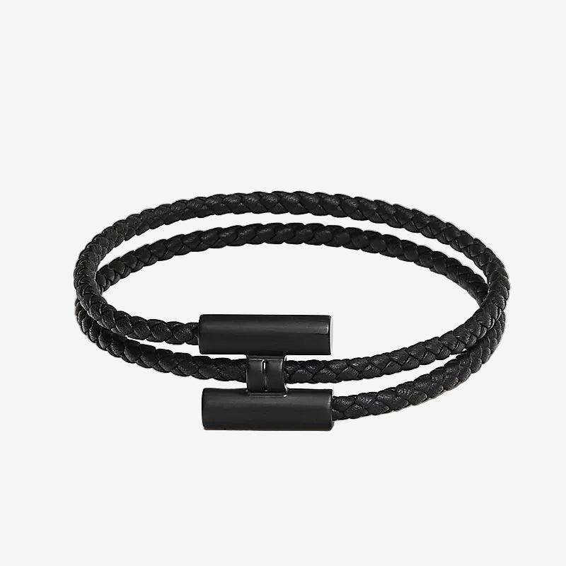 Black braided bracelet with a clasp on a light beige background
