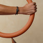 Black braided bracelet with a clasp on a light beige background