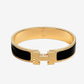 Gold bracelet with black band on a light gray background