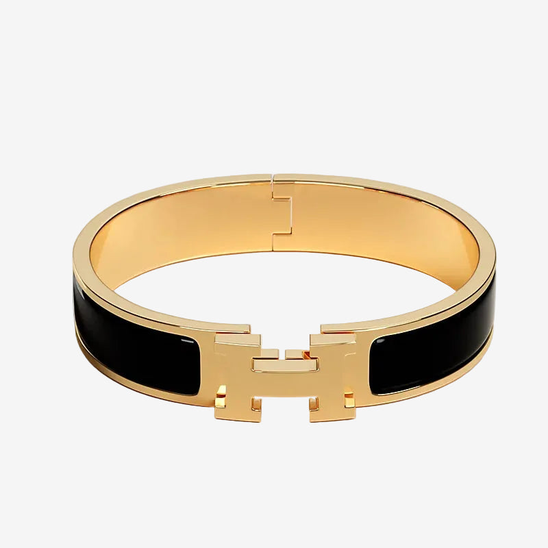 Gold bracelet with black band on a light gray background