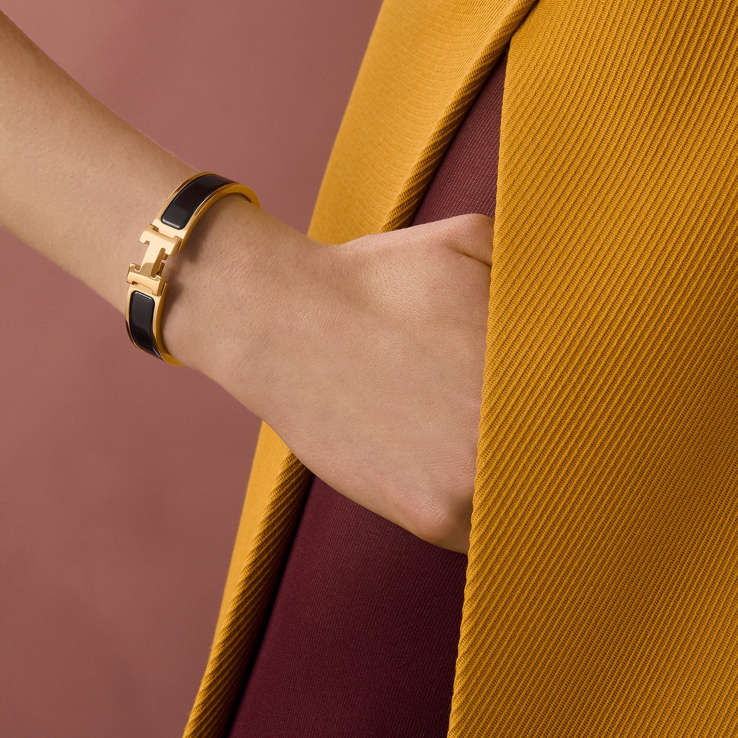 Gold bracelet with black band on a light gray background
