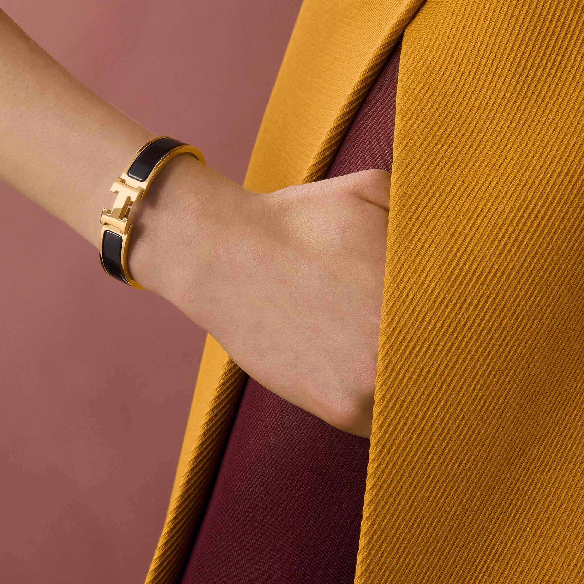 Gold bracelet with black band on a light gray background