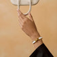 Gold and white bracelet on a light beige background