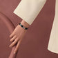 Gold bracelet with black band on a light gray background