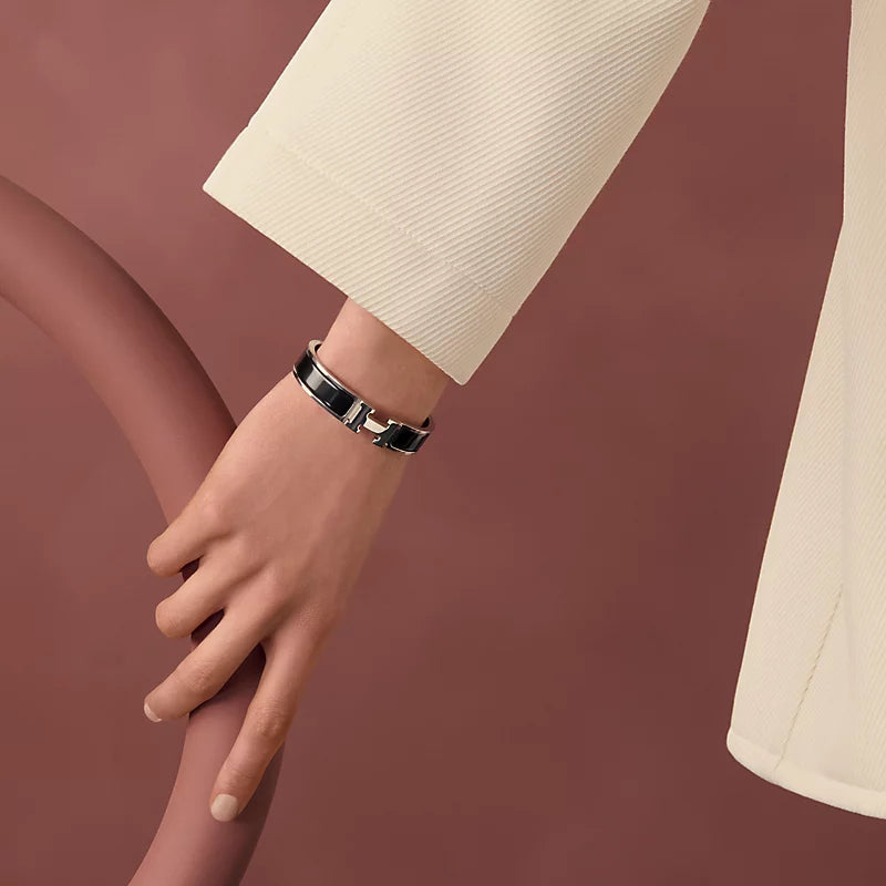 Gold bracelet with black band on a light gray background