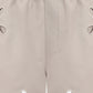 Beige shorts with cut-out designs on a white background
