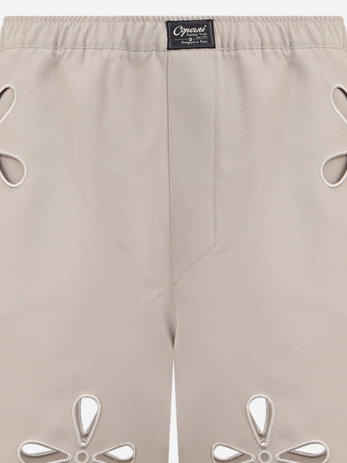 Beige shorts with cut-out designs on a white background