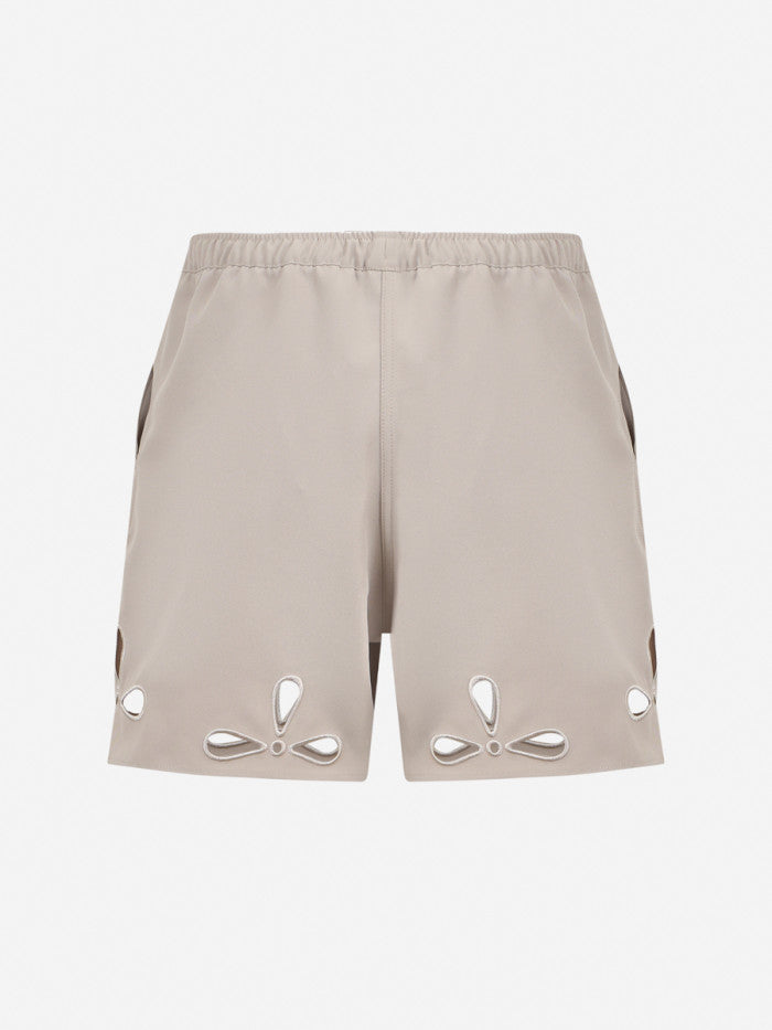 Beige shorts with cut-out designs on a white background
