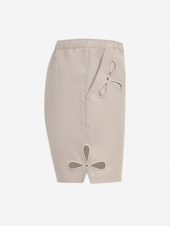 Beige shorts with cut-out designs on a white background
