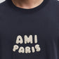 Navy blue t-shirt with 'AMI PARIS' text on a light gray background
