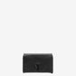 Person holding a black handbag against a neutral background