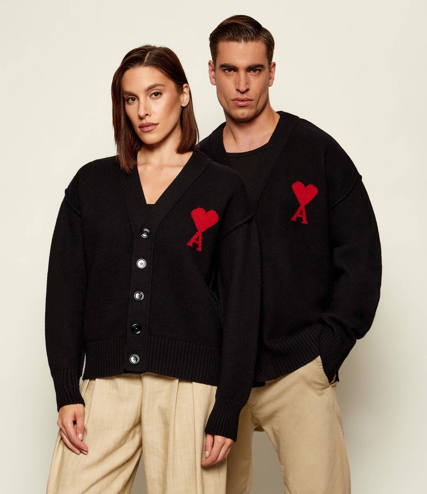 Black cardigan with a red heart emblem on a beige background ami paris