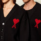 Black cardigan with a red heart emblem on a beige background ami paris