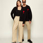 Black cardigan with a red heart emblem on a beige background ami paris