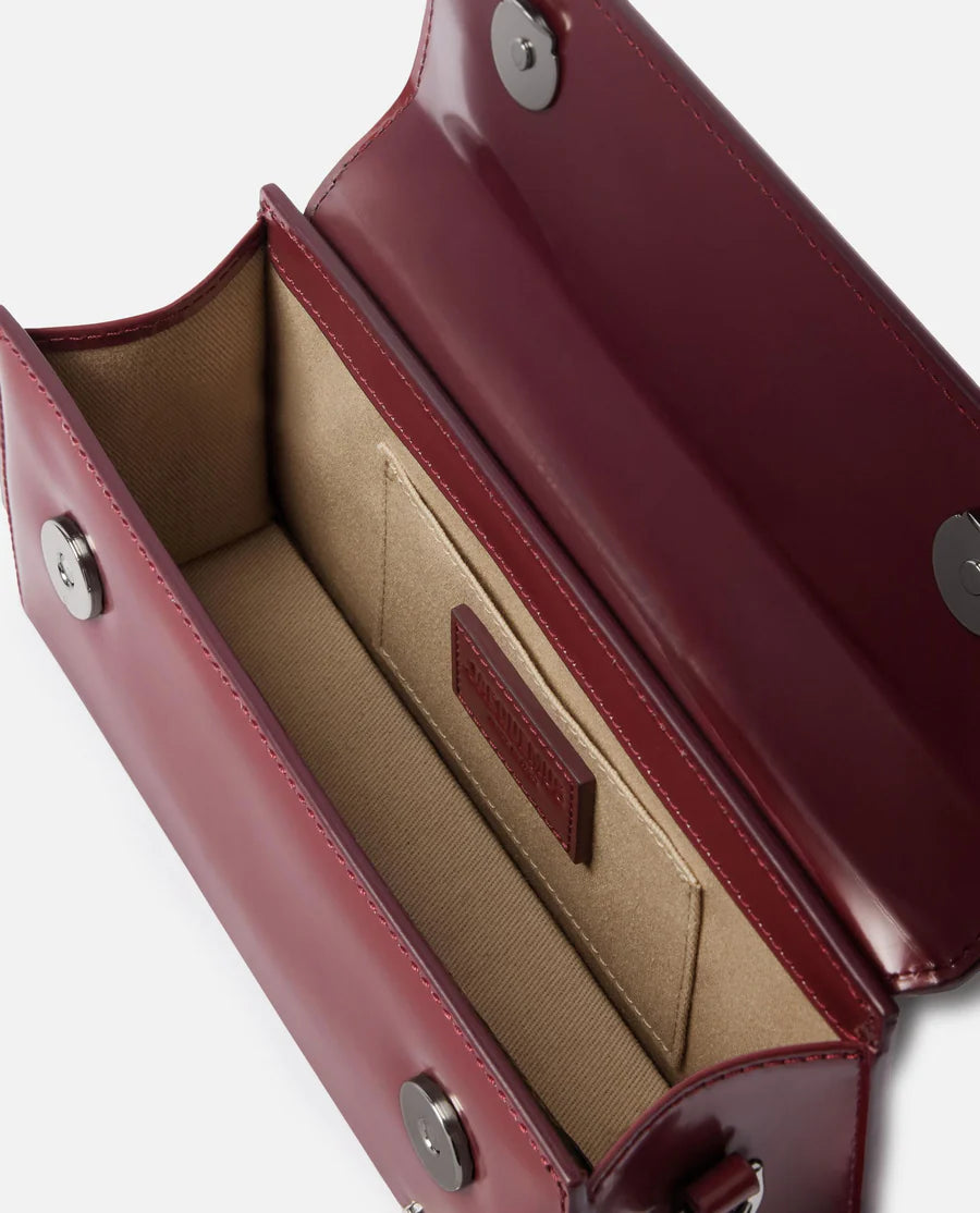 Red handbag with a visible brand logo on a light gray background