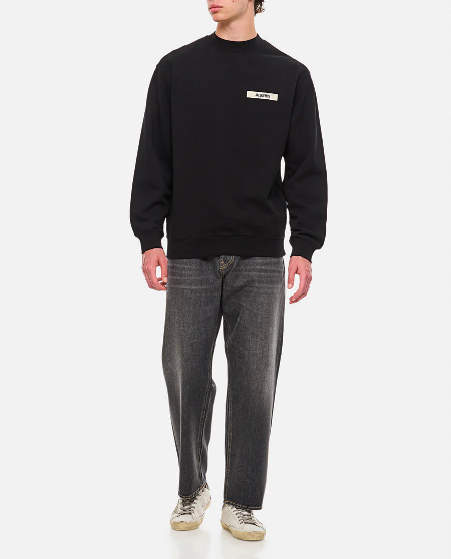Black sweatshirt with a small white logo on a white background