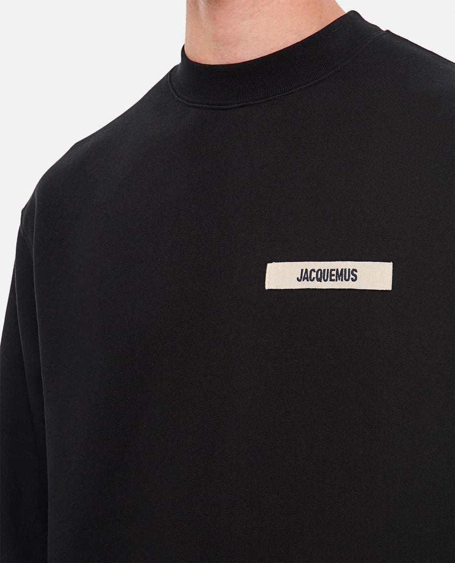 Black sweatshirt with a small white logo on a white background
