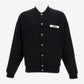 Black varsity jacket with a logo on the chest against a white background