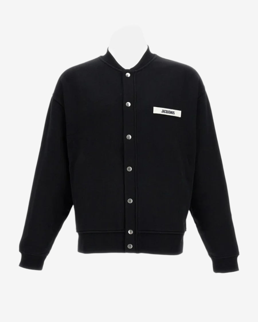 Black varsity jacket with a logo on the chest against a white background