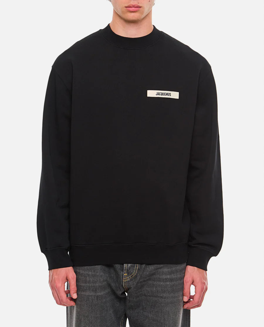 Black sweatshirt with a small white logo on a white background