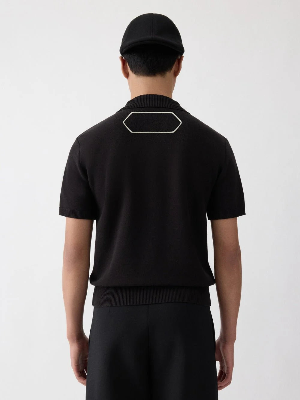 Black polo shirt with a monogram on a white background