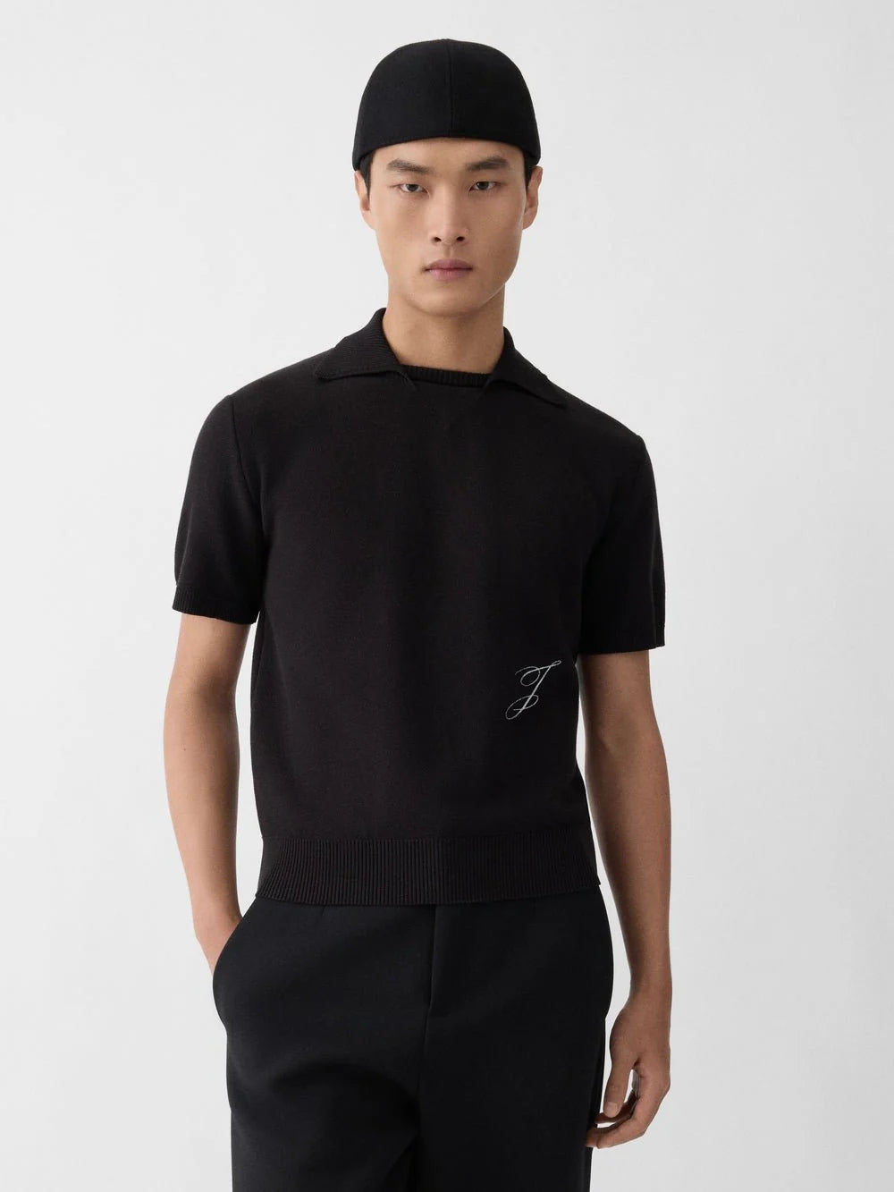 Black polo shirt with a monogram on a white background