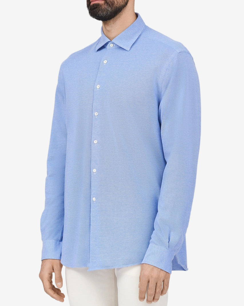 Man wearing a light blue button-up shirt against a white background
