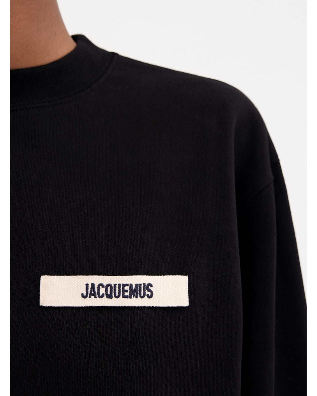 Black sweatshirt with a small white logo on a white background